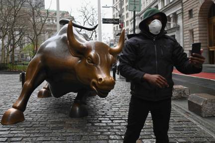 A man wearing a face mask takes a selfie in front of the Charging Bull statue in New York. Photo: AFP