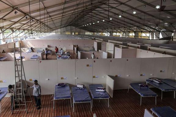 a group of people in a room: Fitting Out and Finishing Touches to a Dedicated Covid Health Centre as India Extends Lockdown